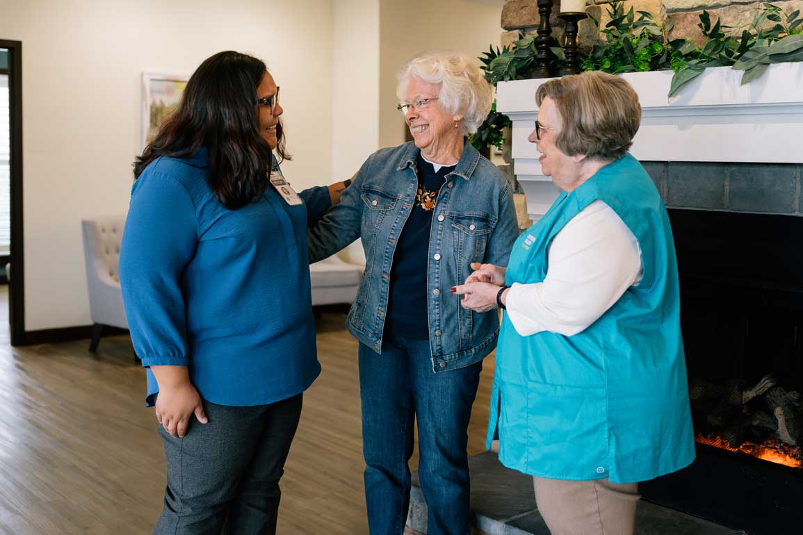Two hospice workers standing beside a senior woman having a conversation