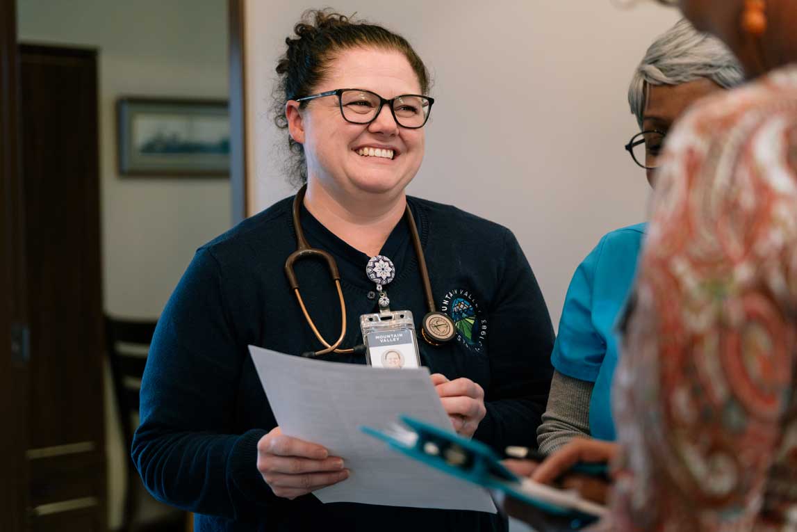 A group of hospice care workers having a discussion while pointing to a paper